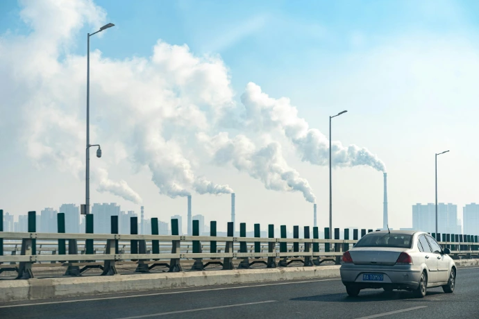 a car driving on a road with a large cloud of smoke behind it